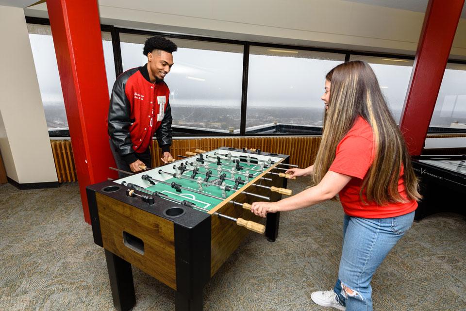 Two students play foosball in the lounge.
