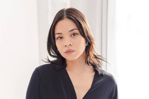Eva Noblezada poses in a dark top with a light background