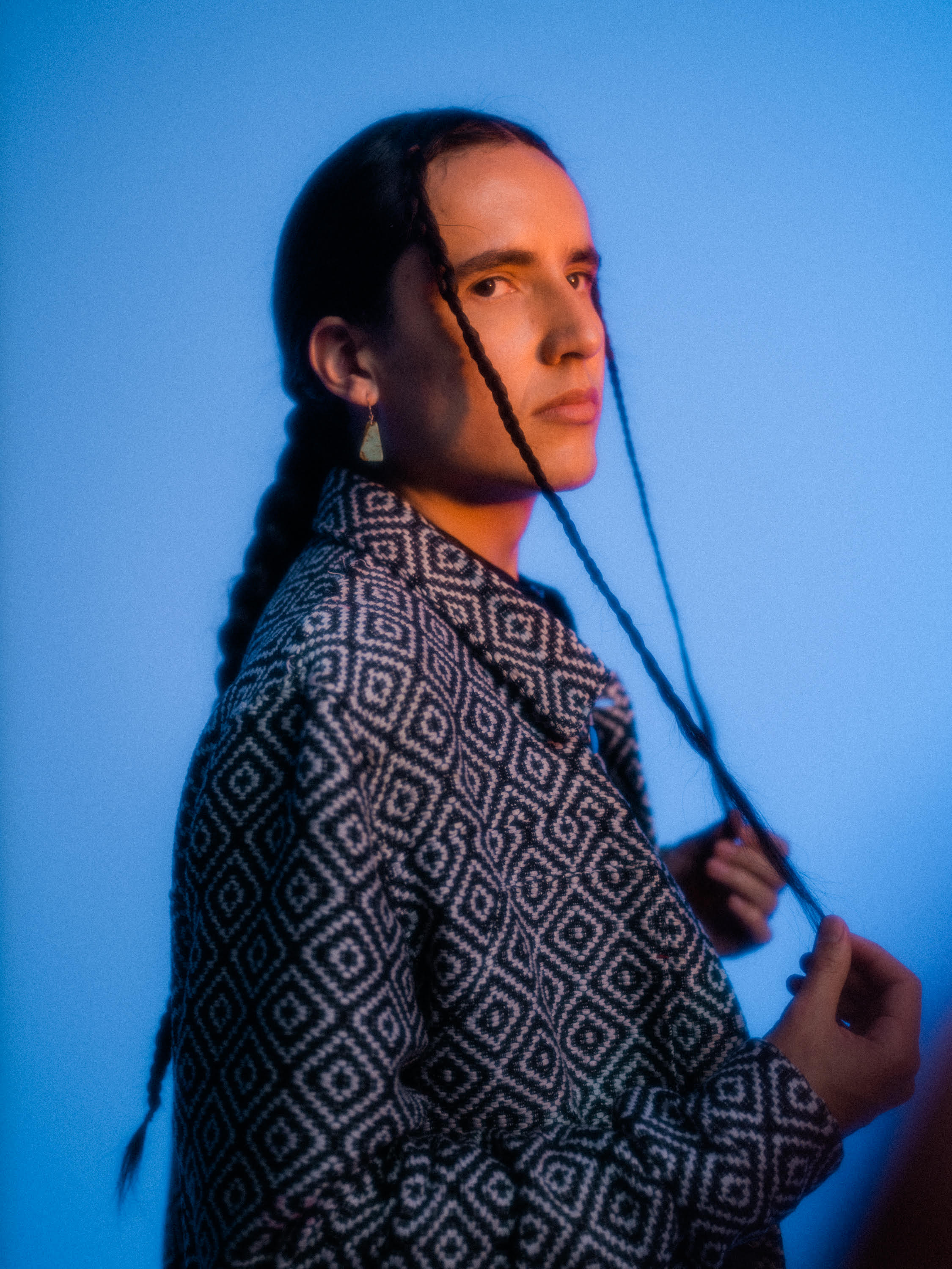 A photo of a man with long dark hair wearing a black and white shirt