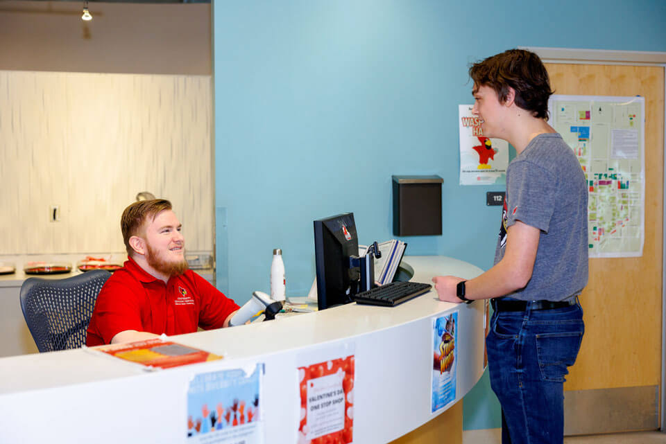 A student speaks to the front desk attendant in Hewett-Manchester.