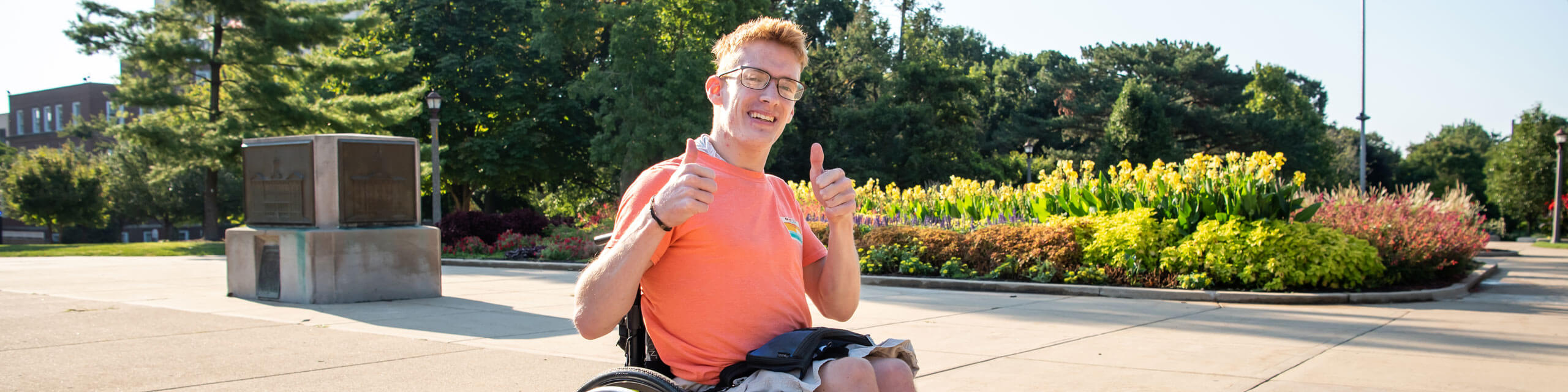 Student in a wheelchair gives two thumbs up to the camera.